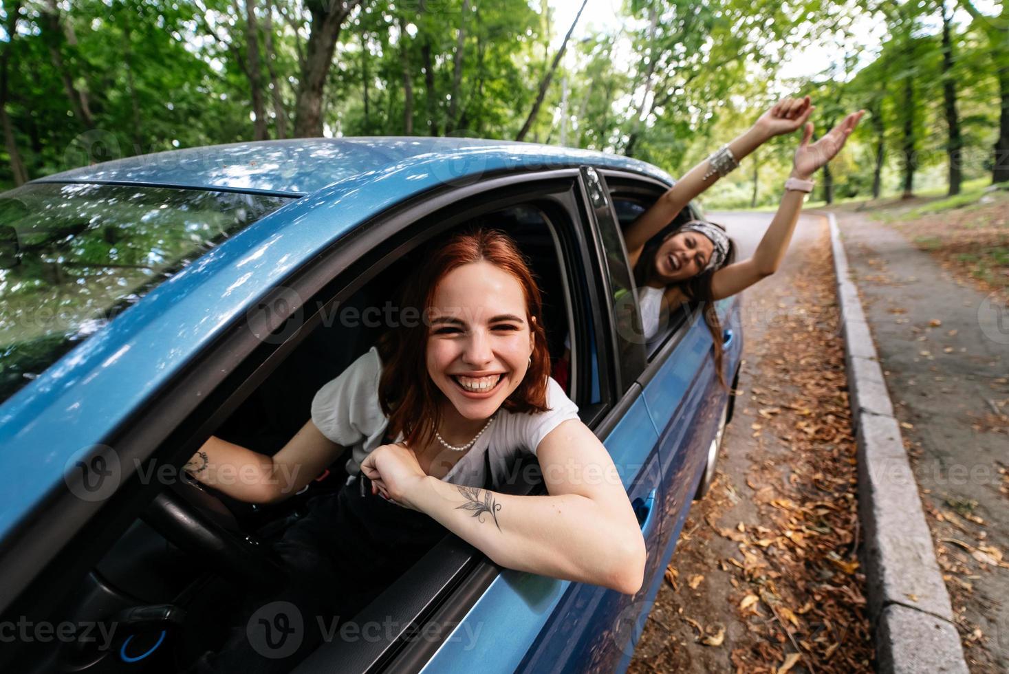 Two girlfriends fool around and laughing together in a car photo