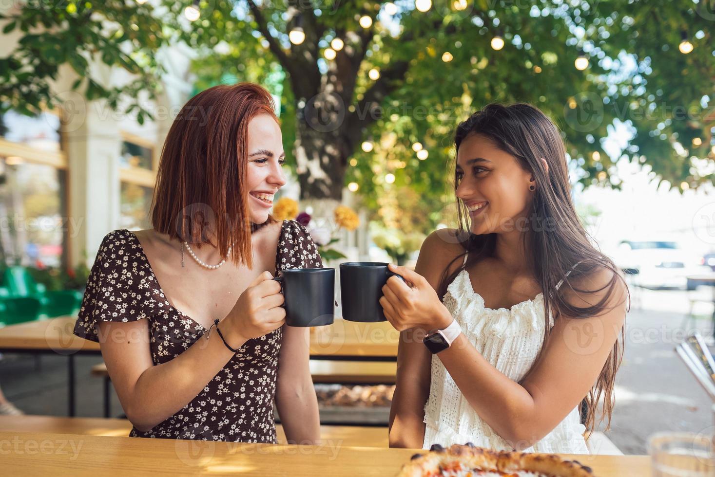 Two friends drinking coffee - women clinking with cups of coffee photo