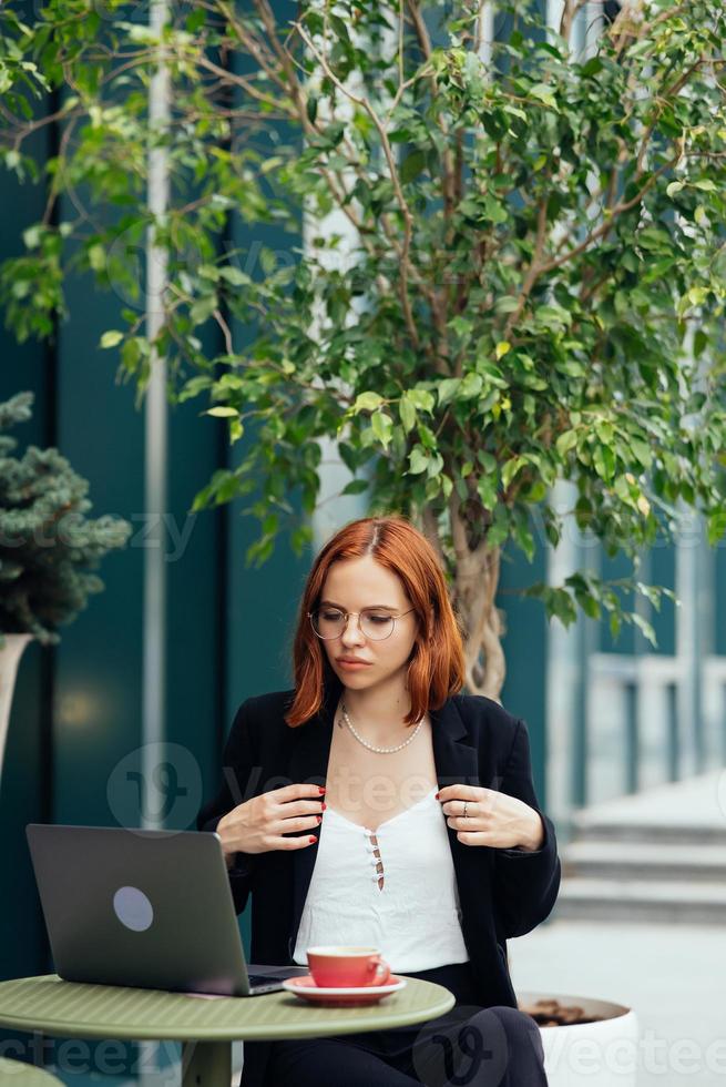 Beautiful woman working on laptop at outdoors cafe photo
