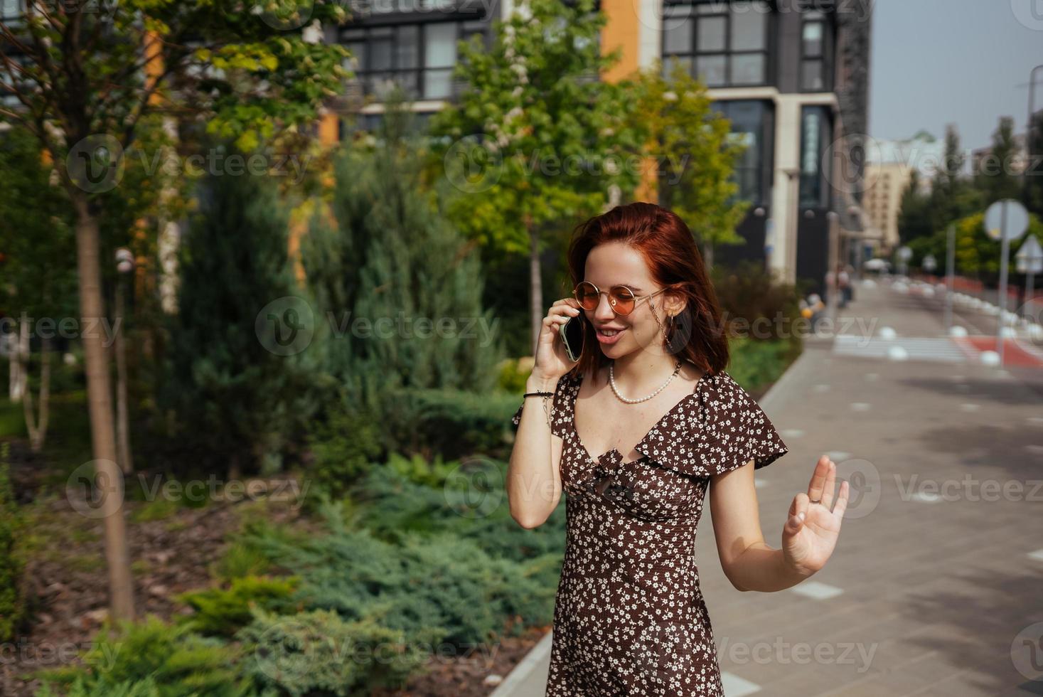 Cute girl talking on mobile phone on modern city background photo