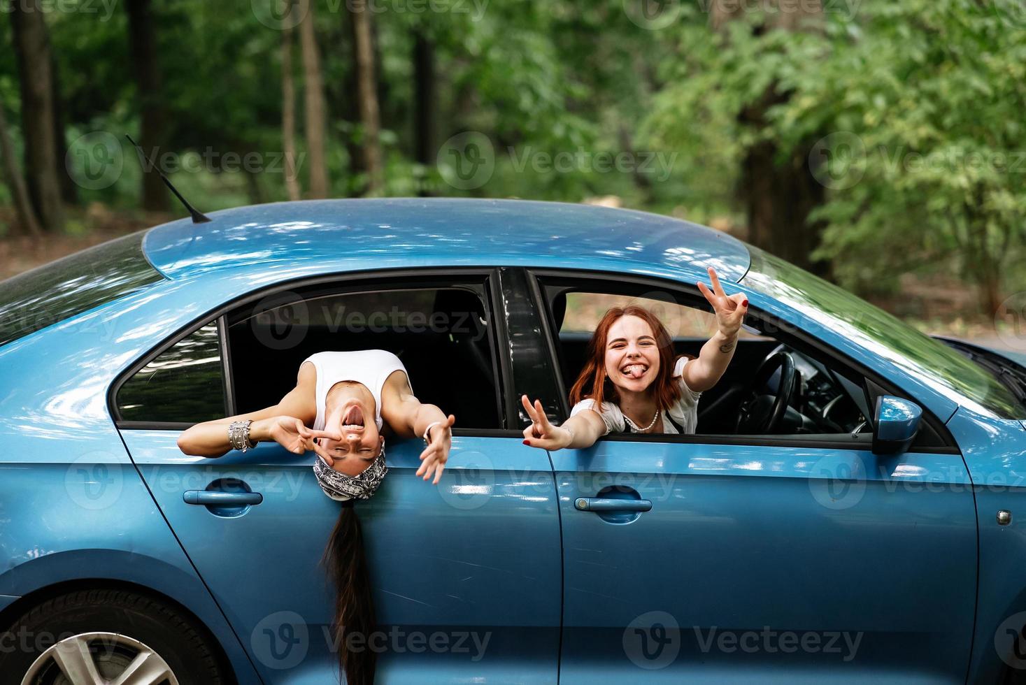 Two girlfriends fool around and laughing together in a car photo