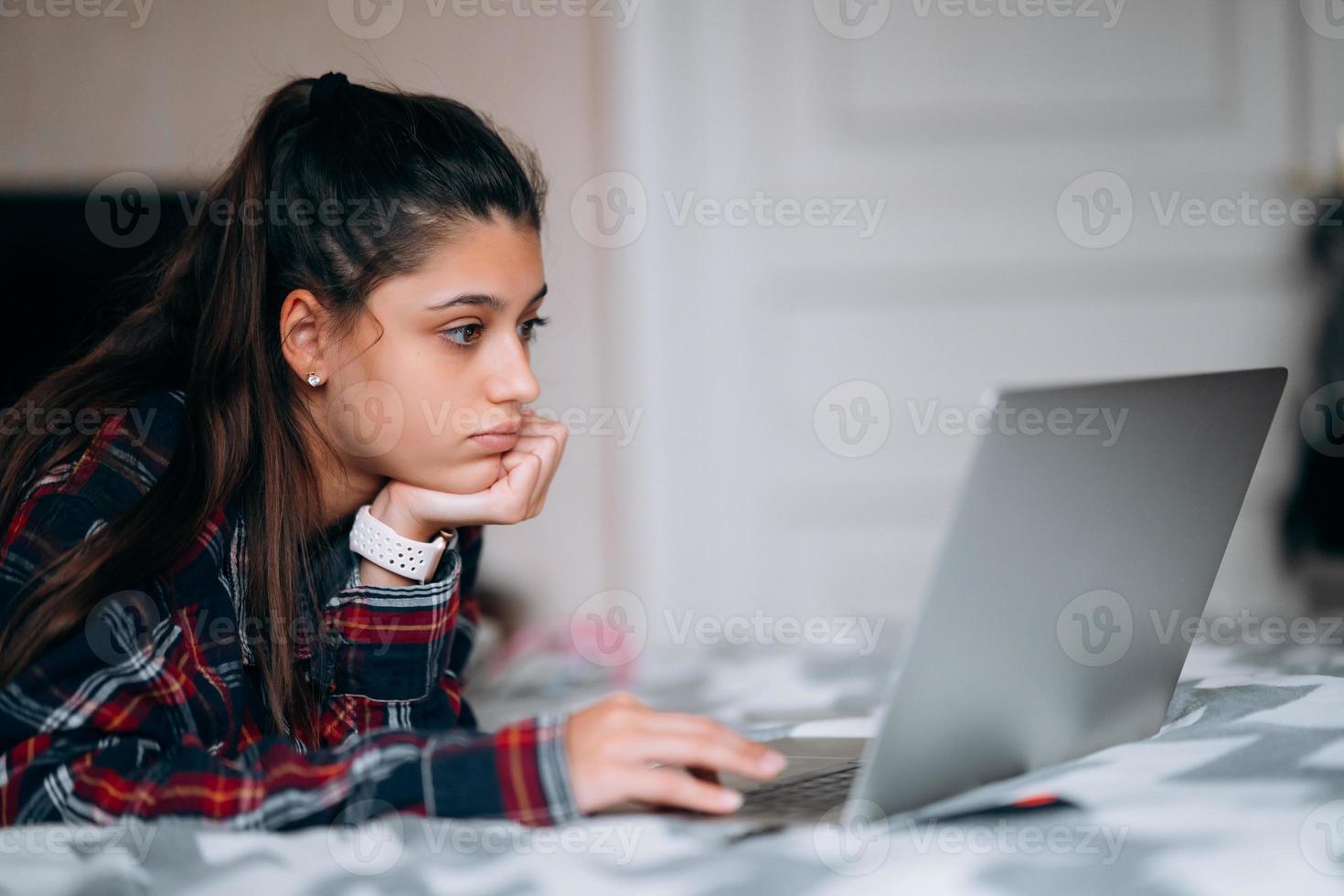 mujer joven trabaja mientras tiene una laptop acostada en la cama foto