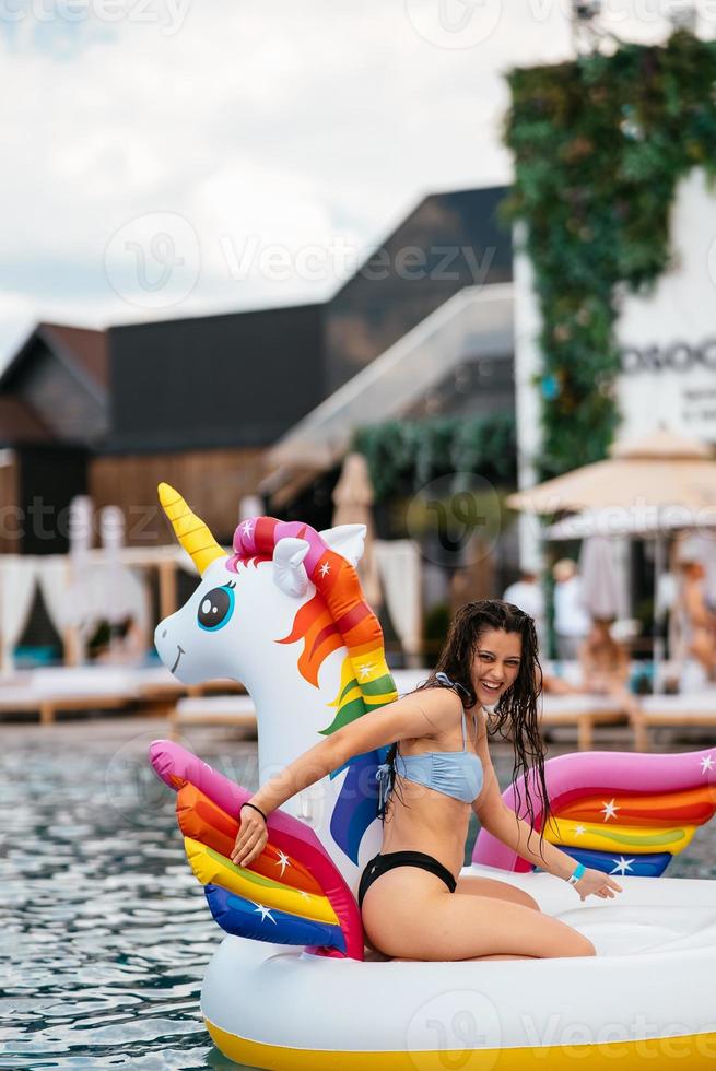 Woman on inflatable unicorn toy mattress float in pool. photo