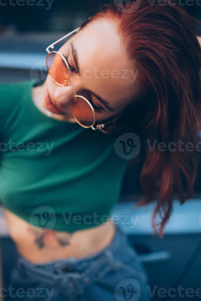 Beautiful fashionable young woman in glasses posing near car photo