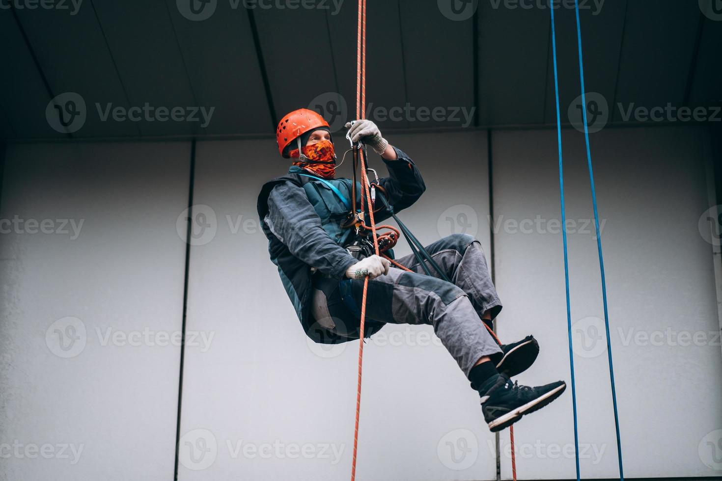 Industrial climber in uniform and helmet rises photo