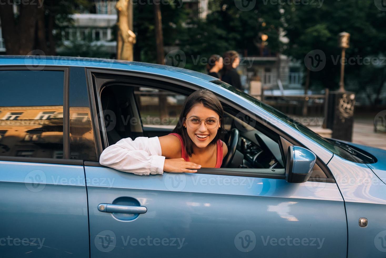 Happy woman in a car, looking out of the window. photo