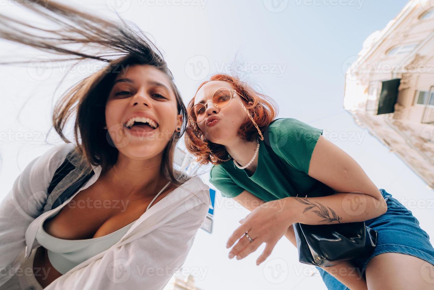 Two friends looks down outdoors in the street at camera photo