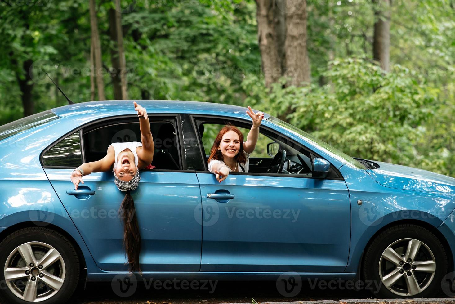 Two girlfriends fool around and laughing together in a car photo