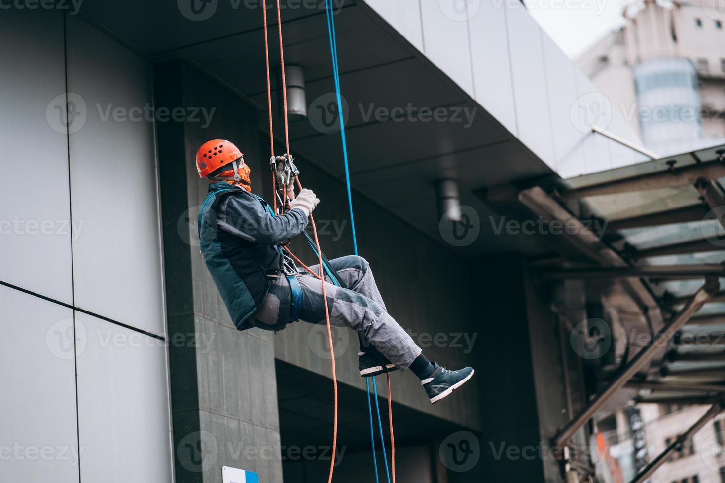 Industrial climber in uniform and helmet rises photo