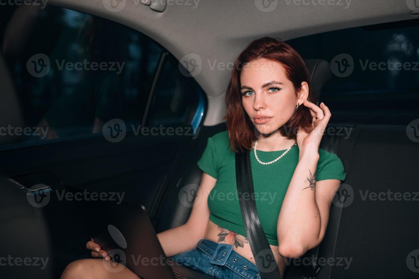 Beautiful woman is using laptop while sitting on back seat photo