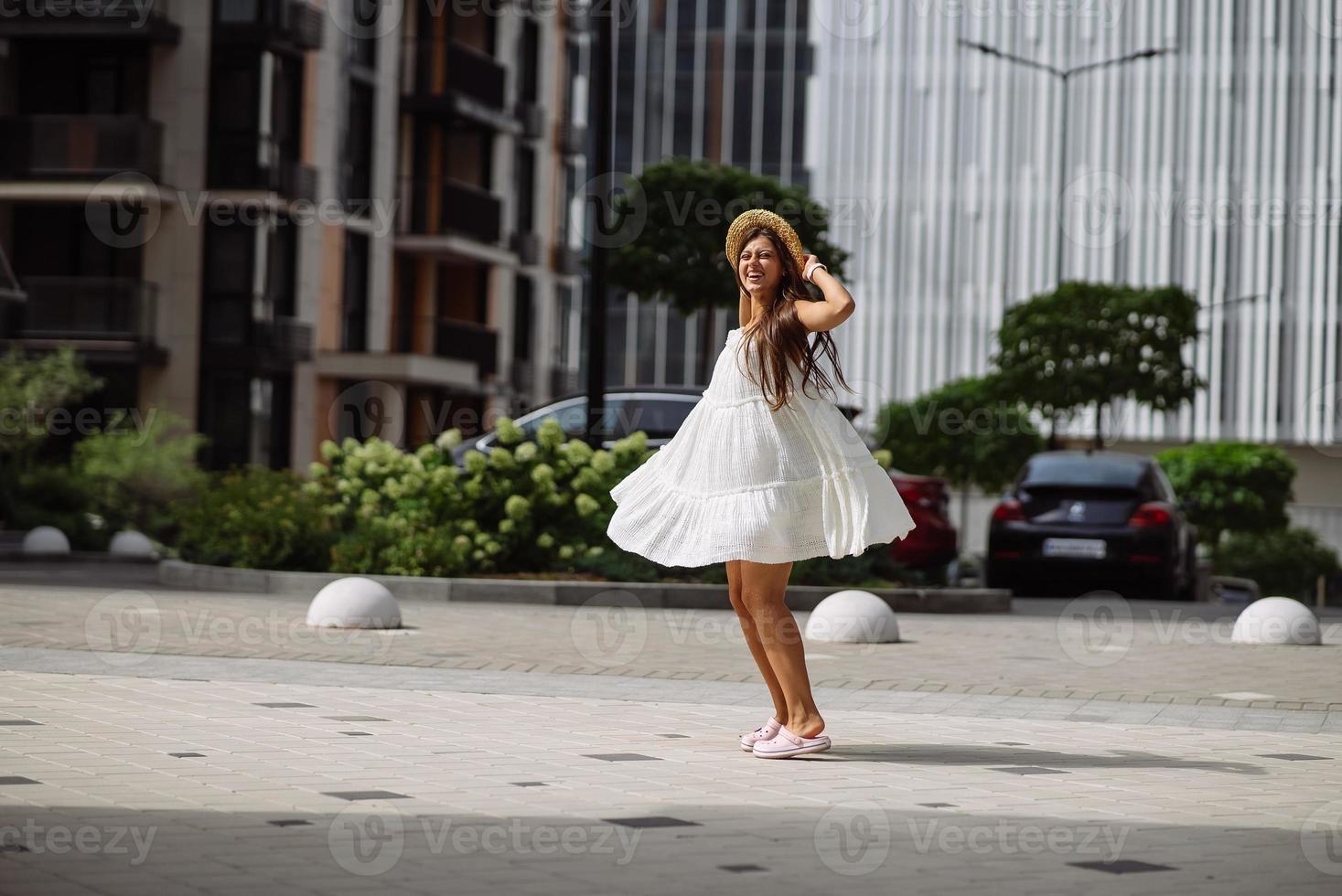 hermosa mujer bonita con vestido blanco caminando por la calle de la ciudad foto