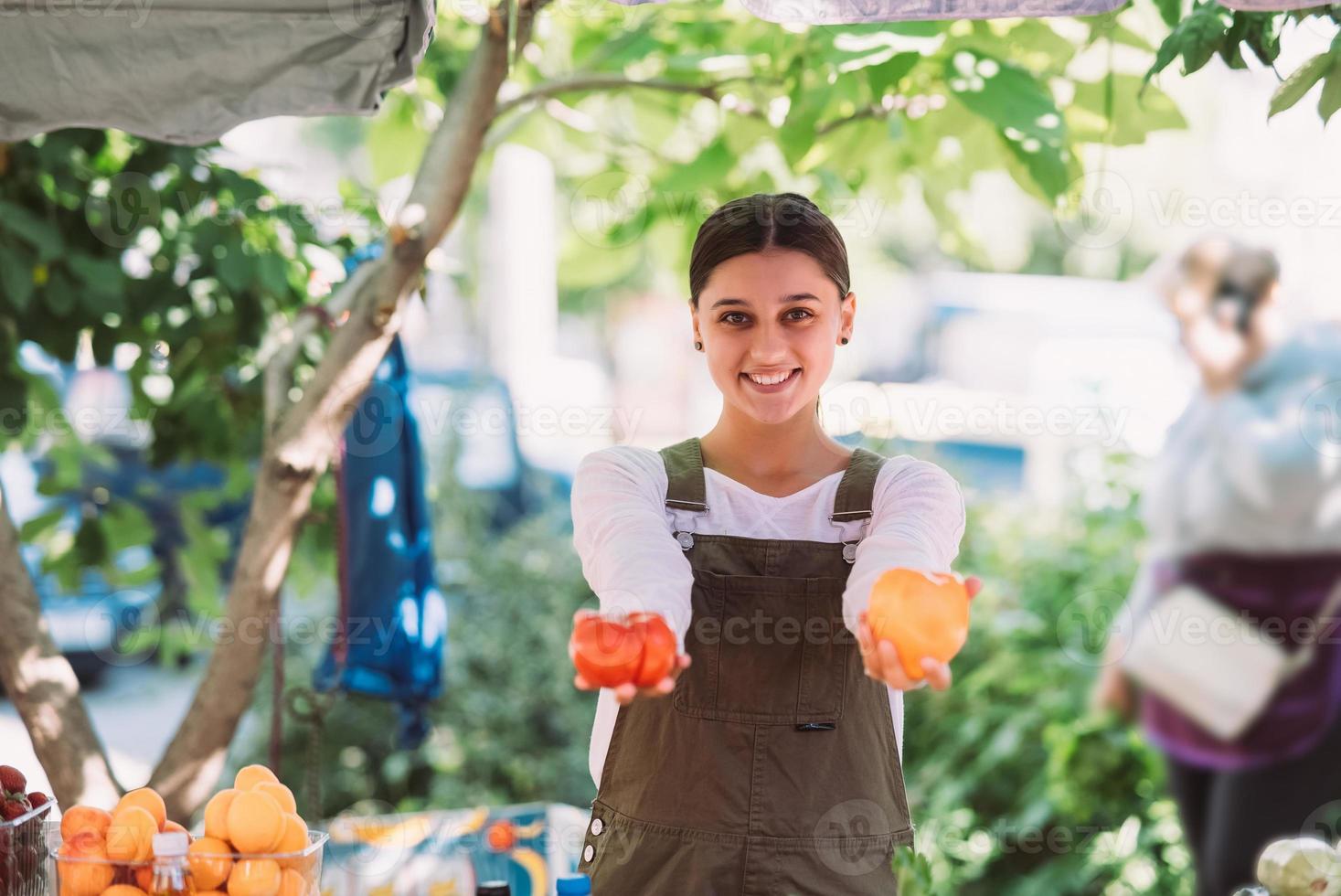 Young saleswoman holding home-grown tomatos in hands photo