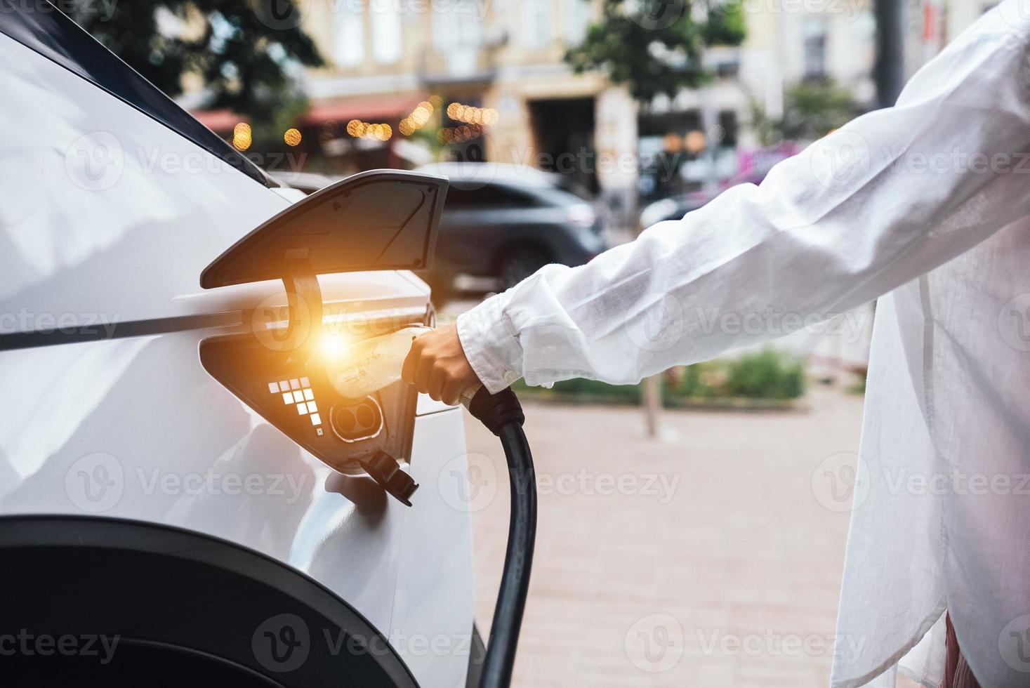 Human hand is holding Electric Car Charging nozzle. photo