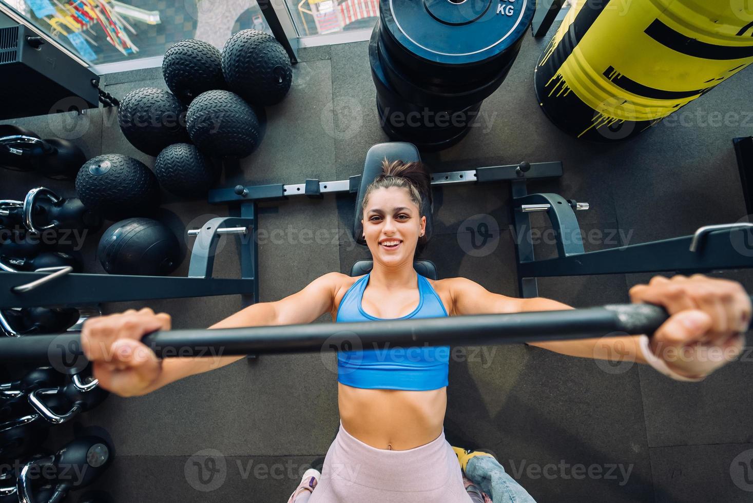 Woman doing exercises with barbell on a bench press training photo