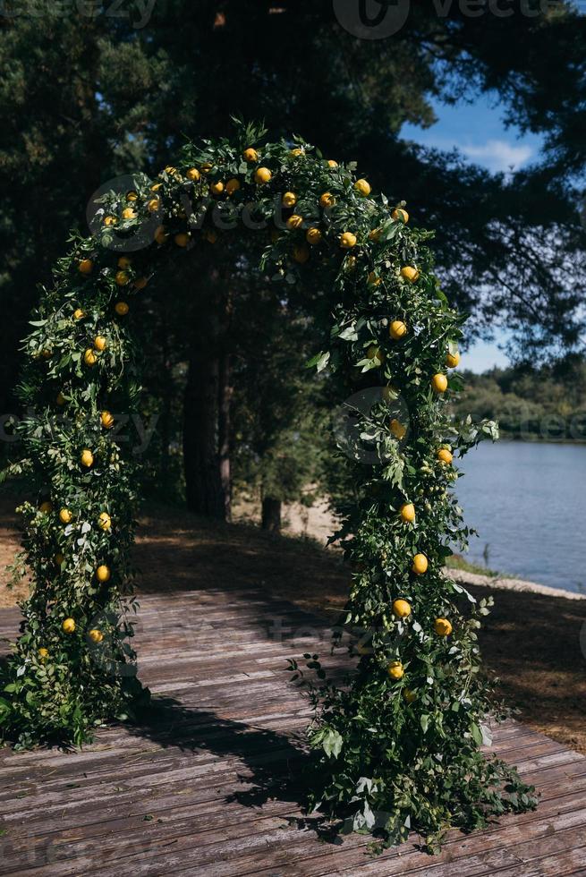 el arco de la boda está decorado con hojas verdes y limones. foto