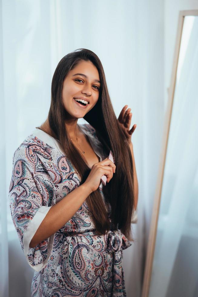 hermosa joven peinándose frente a su espejo. foto