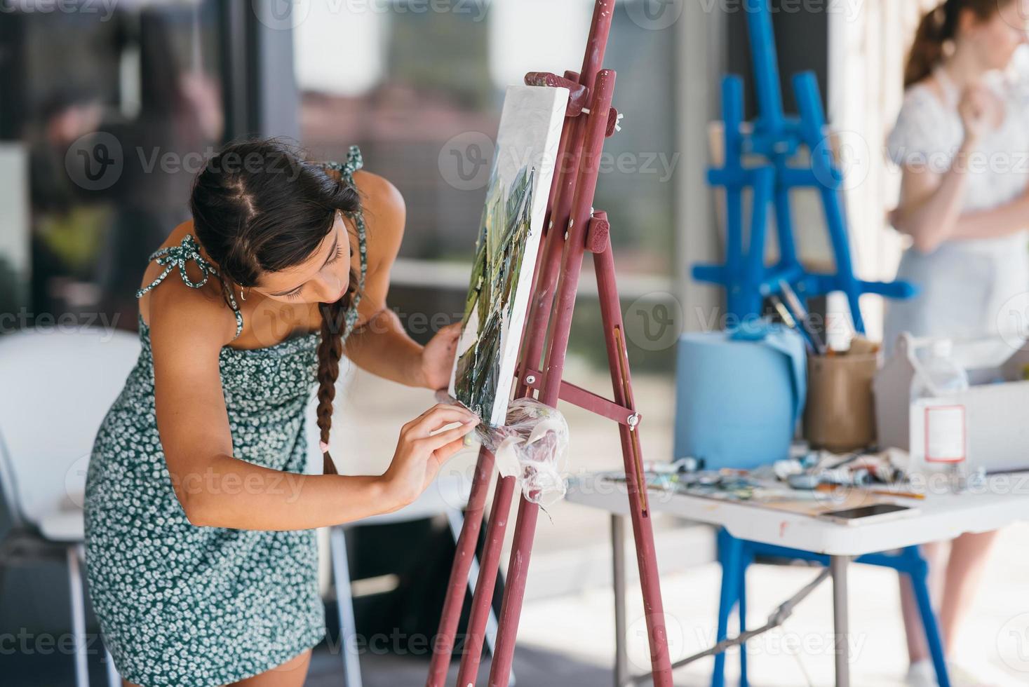 Young woman artist paints with a spatula on the canvas photo