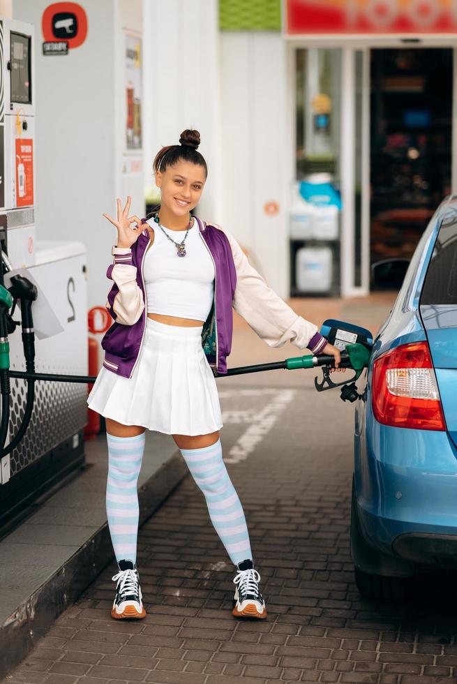 Woman filling her car with fuel at a gas station photo