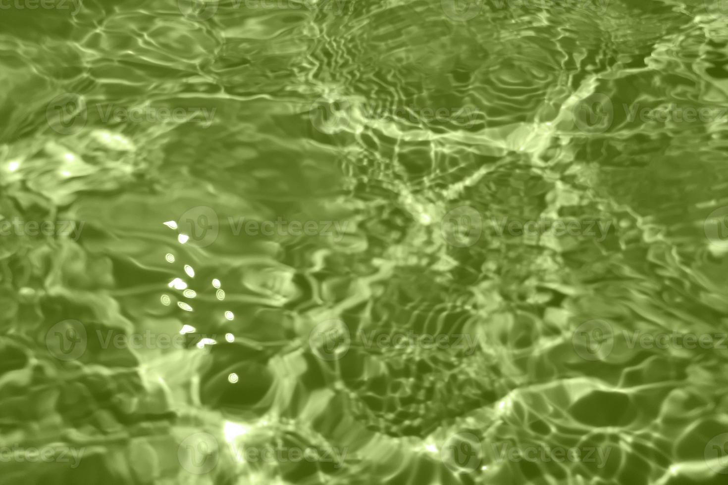 Defocus blurred transparent green colored clear calm water surface texture with splashes and bubbles. Trendy abstract nature background. Water waves in sunlight with copy space. Green watercolor shine photo