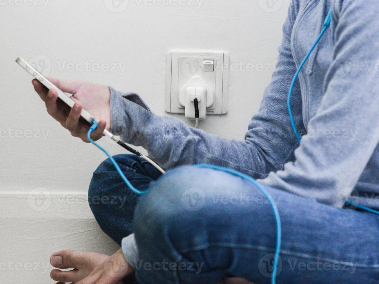 A girl next to wall power outlet to charge her phone photo