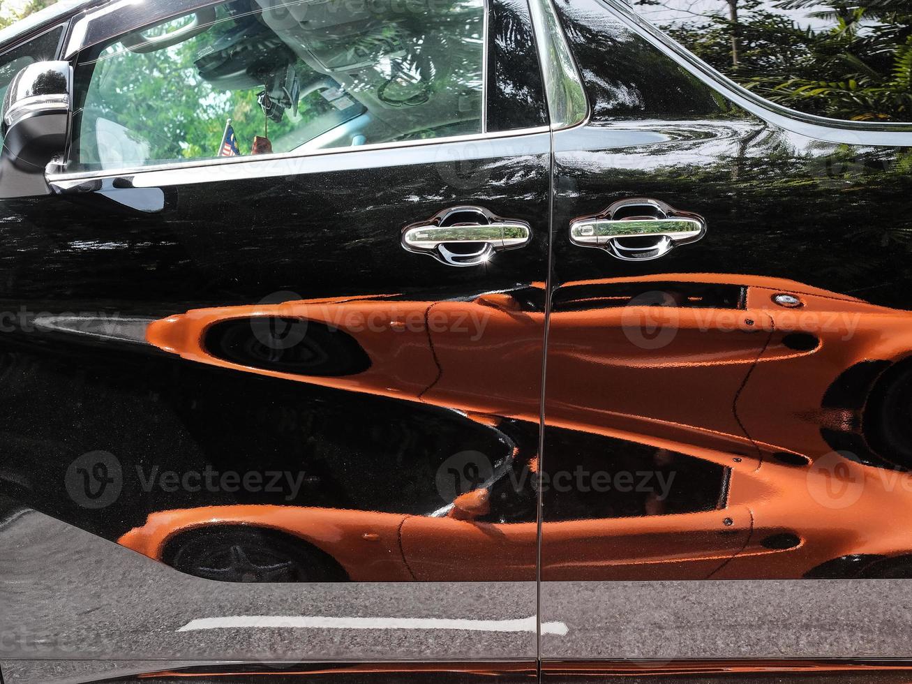 Reflection of an orange car on a black van photo