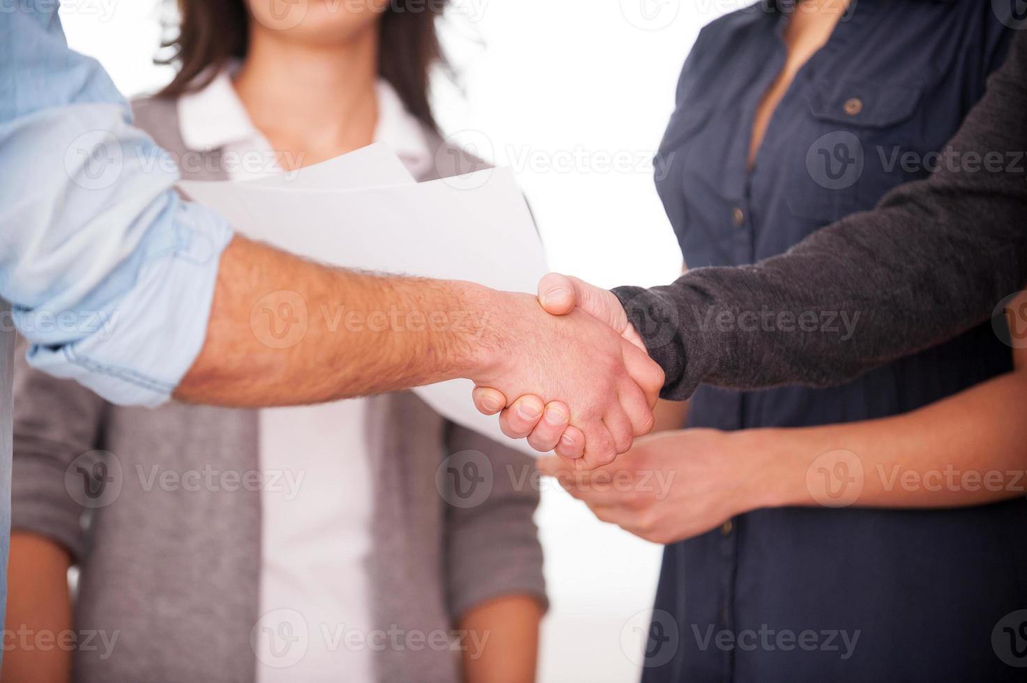 Welcome on board Two cheerful young men handshaking while two women looking at them and smiling photo