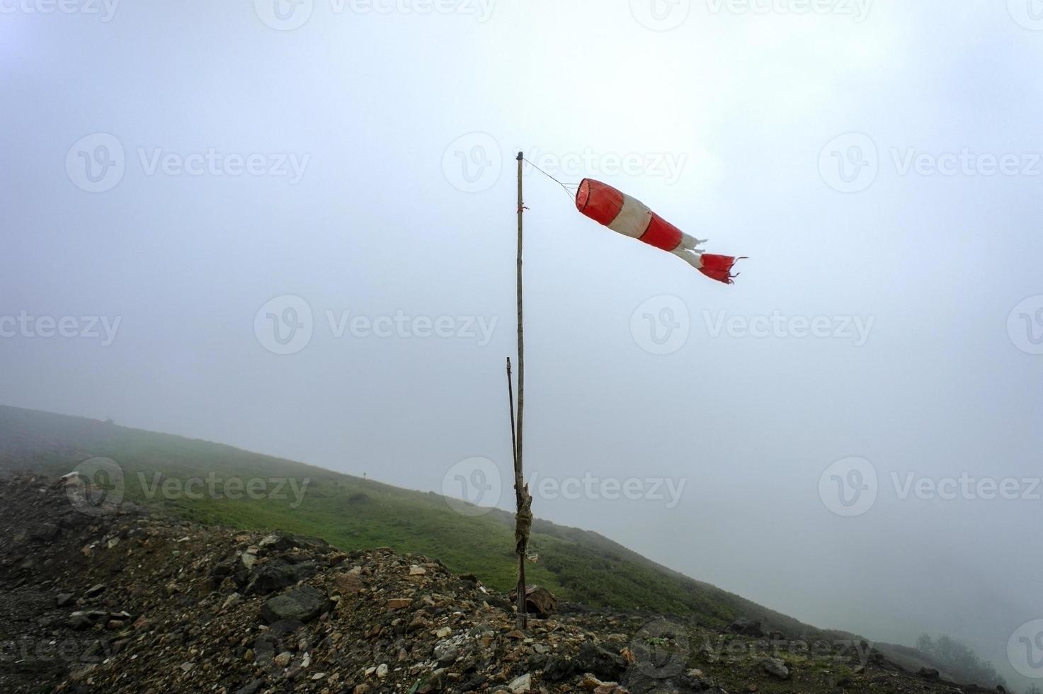 Manga de viento rayada antigua, indicador de la fuerza y dirección del viento en las montañas del Cáucaso en la niebla foto