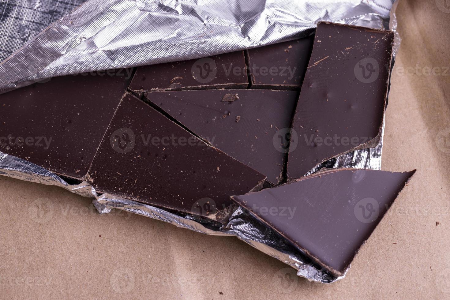 A broken chocolate bar in a paper and foil package photo