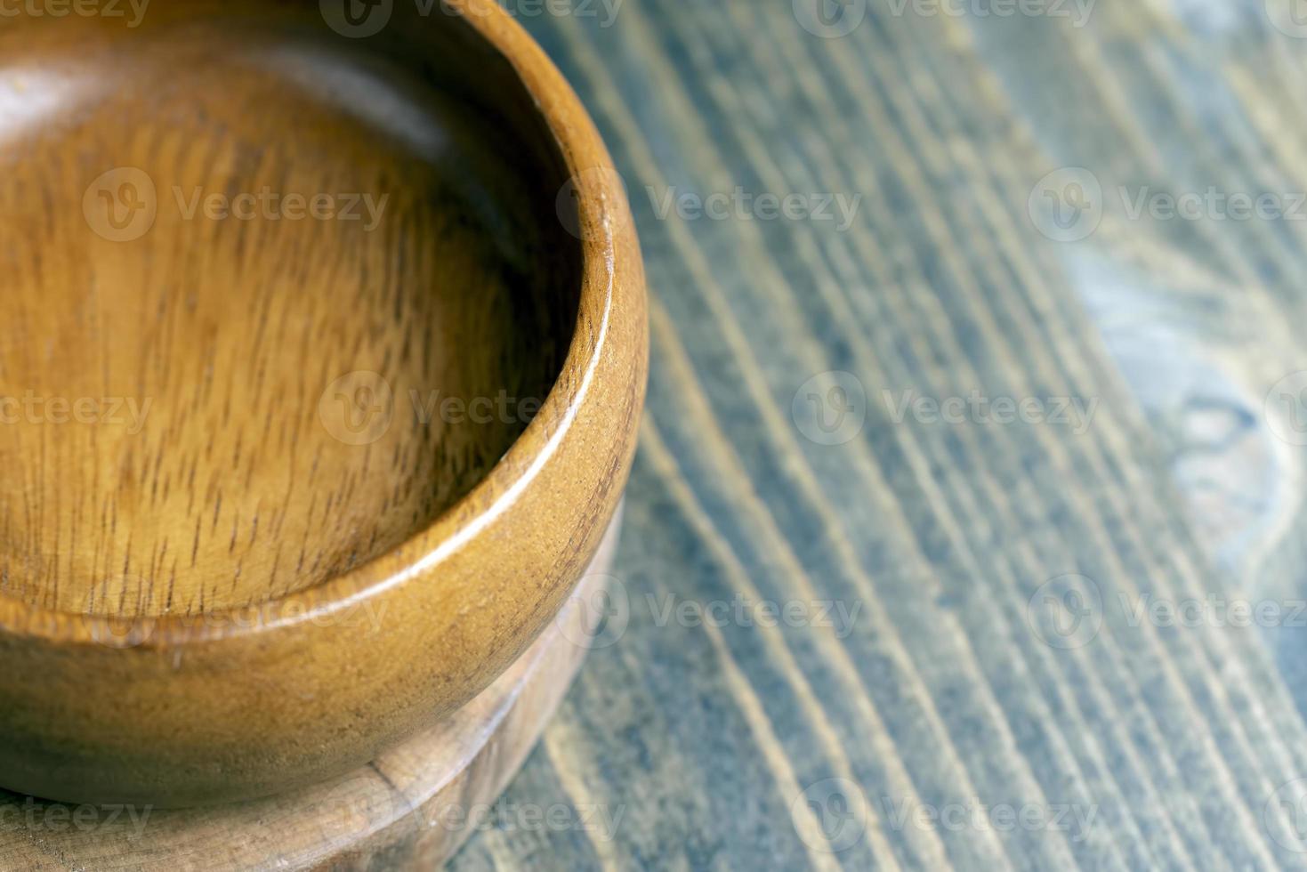 Wooden bowl on wooden table, empty round bowl for groceries and food photo