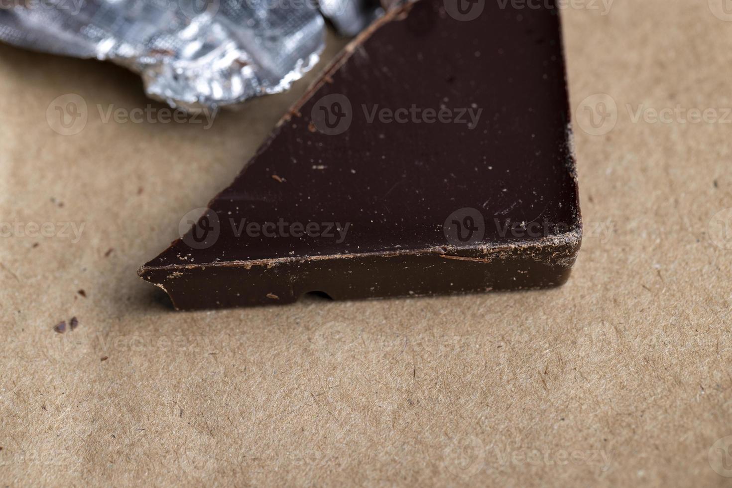 A broken chocolate bar in a paper and foil package photo
