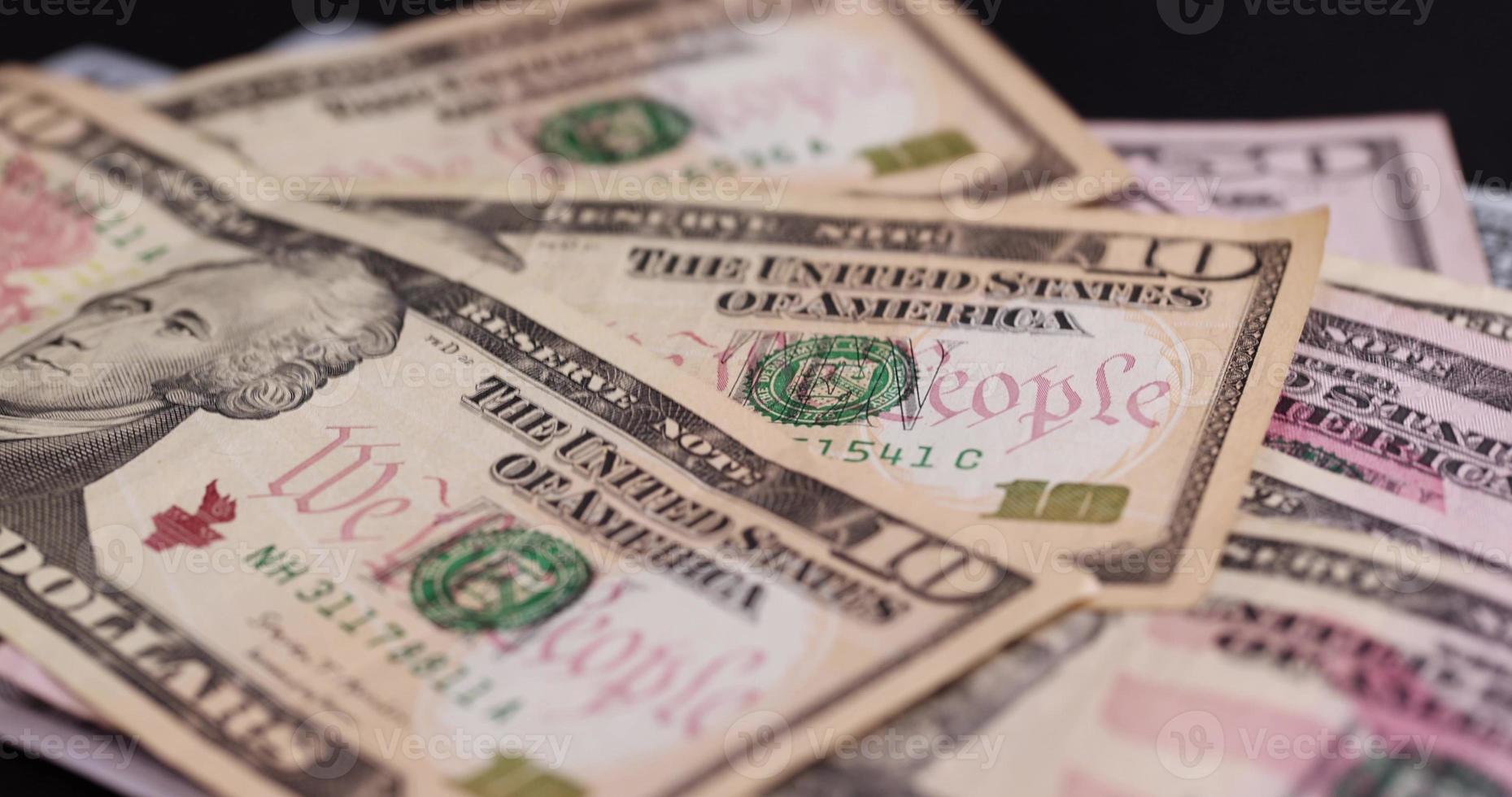 folding American cash ten-dollar bills on black paper photo