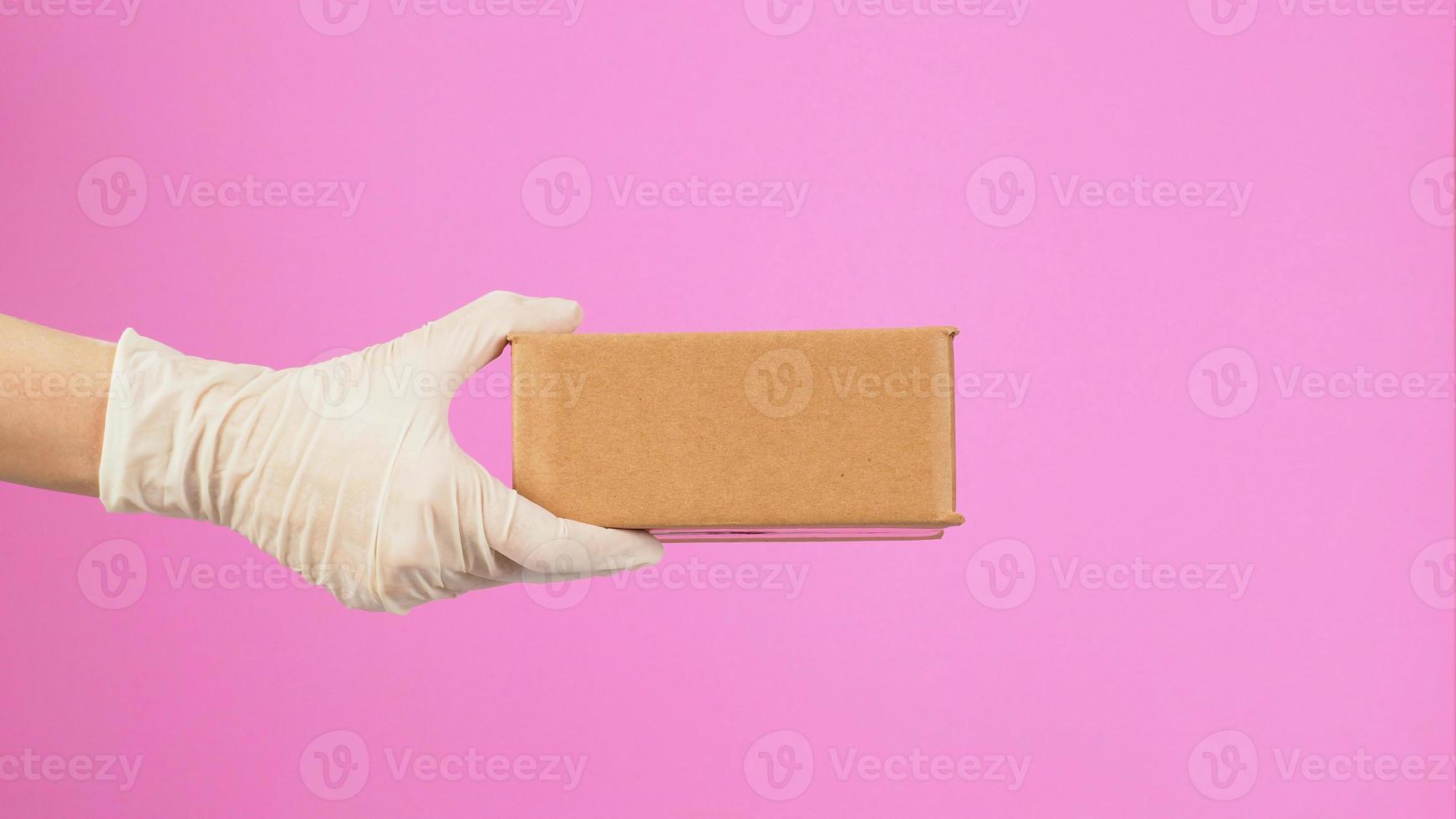 The hand is holding a brown box isolated on pink background.side view photo