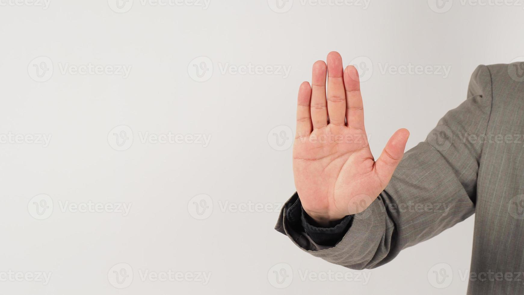 la mano no hace o detiene un signo de mano en un traje gris sobre fondo blanco. foto