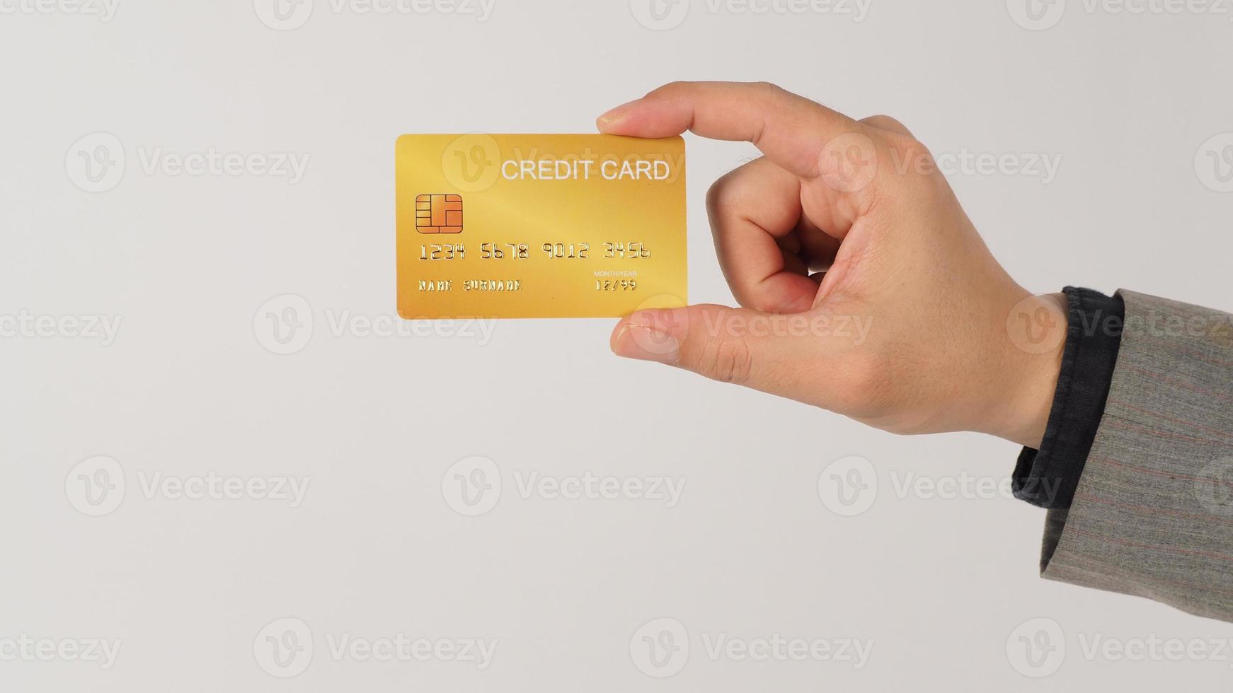 la mano sostiene una tarjeta de crédito dorada y lleva traje de fondo blanco. foto