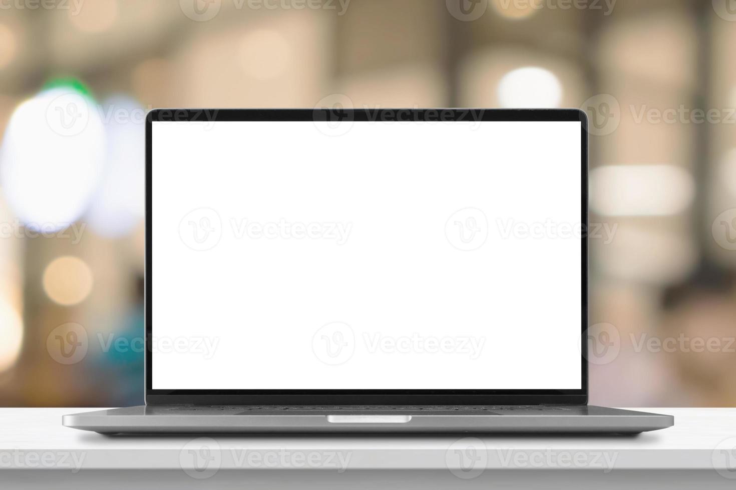 Laptop with blank screen on marble table with cafe coffee shop blur background photo