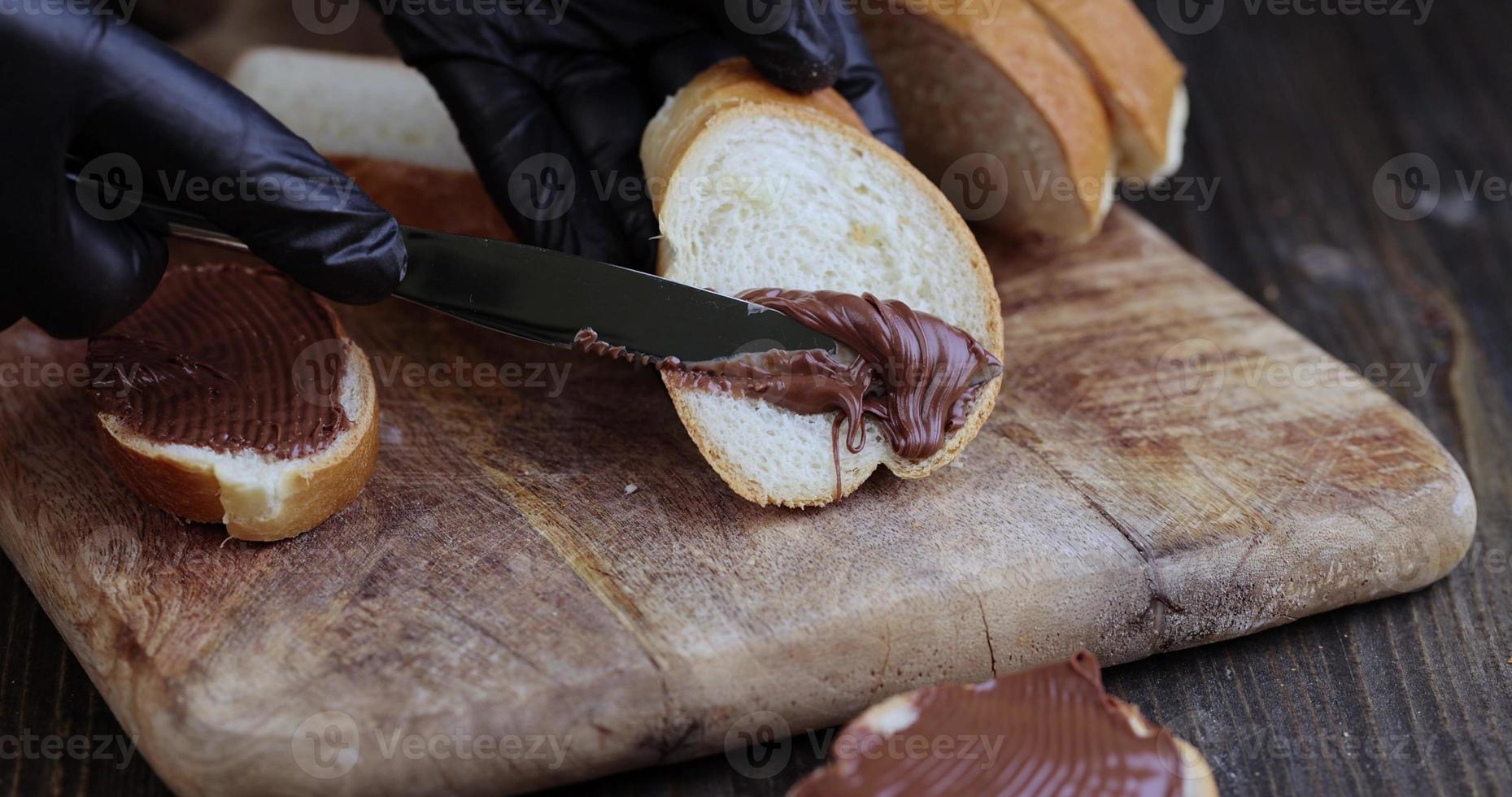 spread chocolate butter on a baguette, close up photo