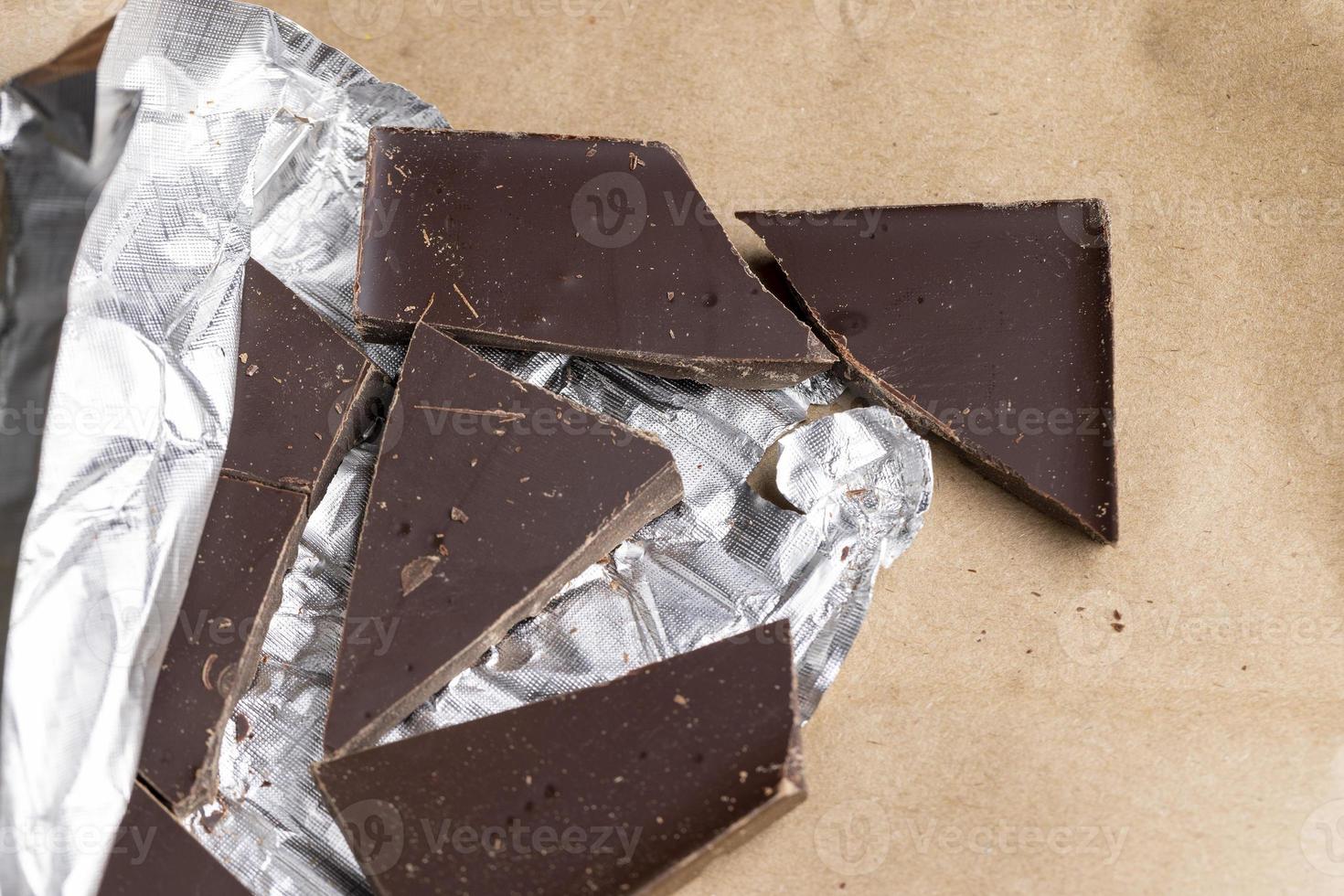 A broken chocolate bar in a paper and foil package photo