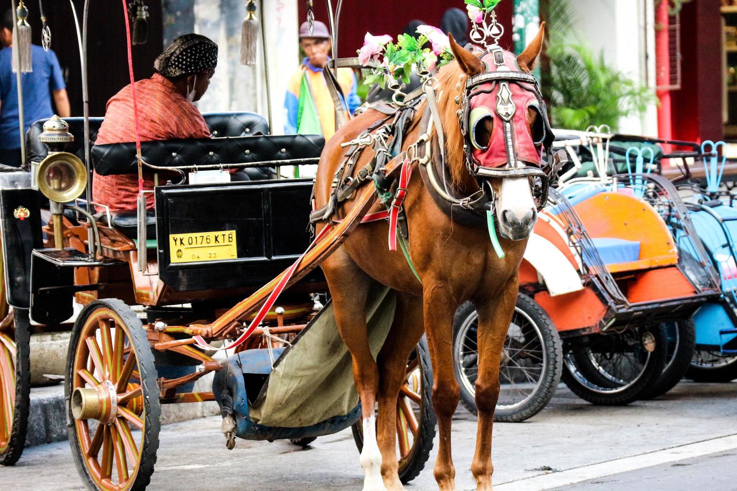 Yogyakarta, Indonesia on October 23, 2022. Andong or horse-drawn carriage with its coachman parked on Jalan Malioboro, waiting for passengers. photo