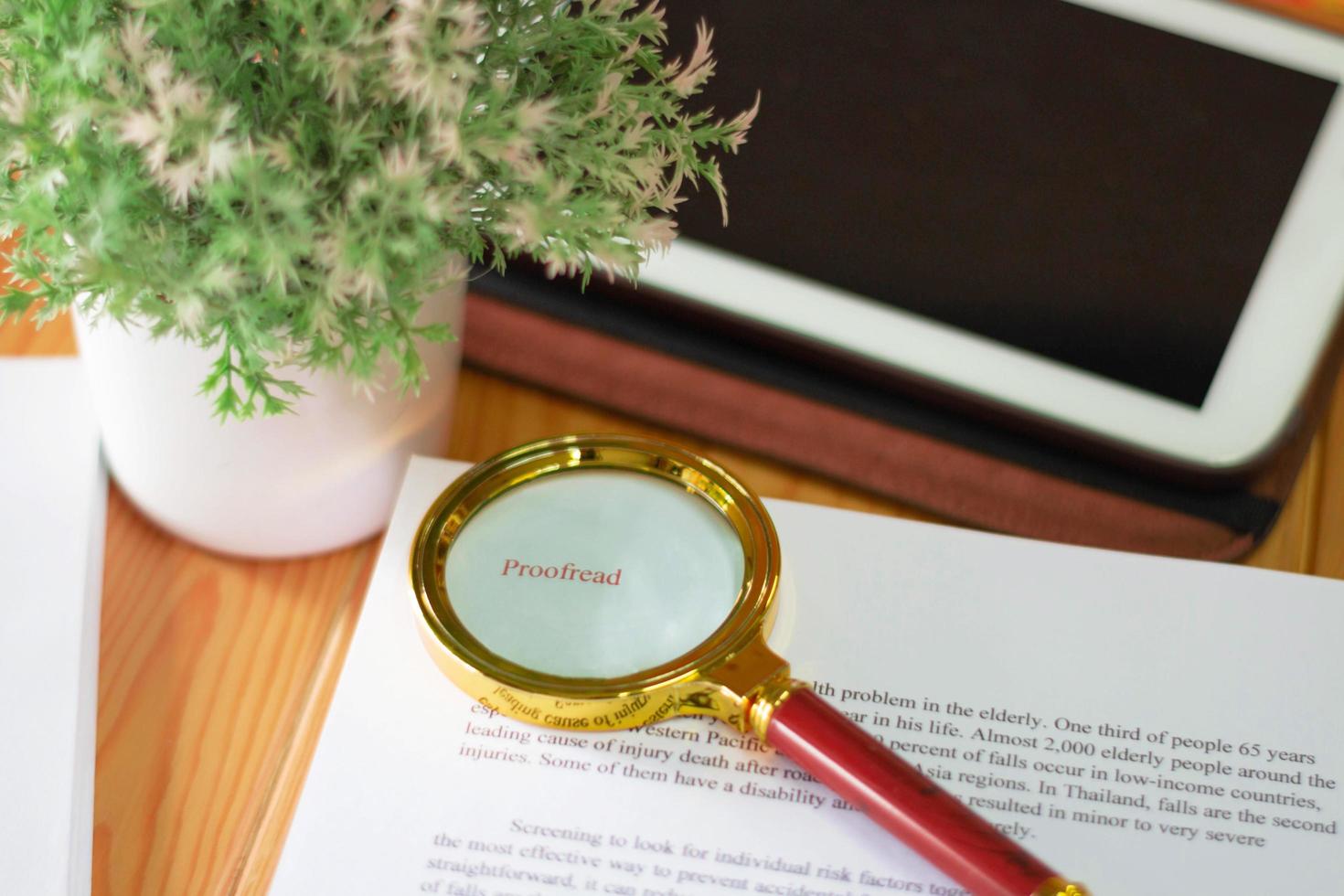 close up new golden maginifier on proofreading paper on wooden table with office supply photo