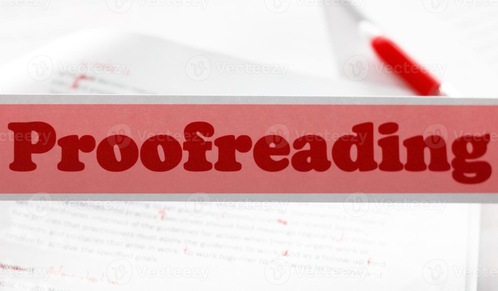 red proofreading sign over blurred paperwork on white table photo