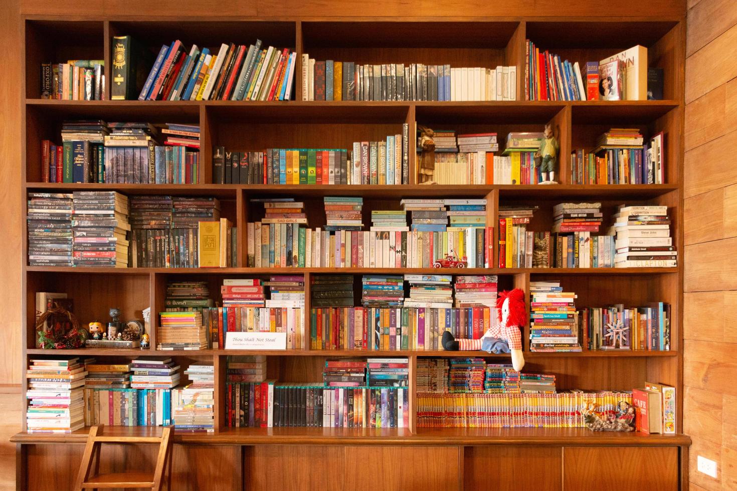 varios tipos de libros en estantes de madera con una colección de figuras de juguete foto