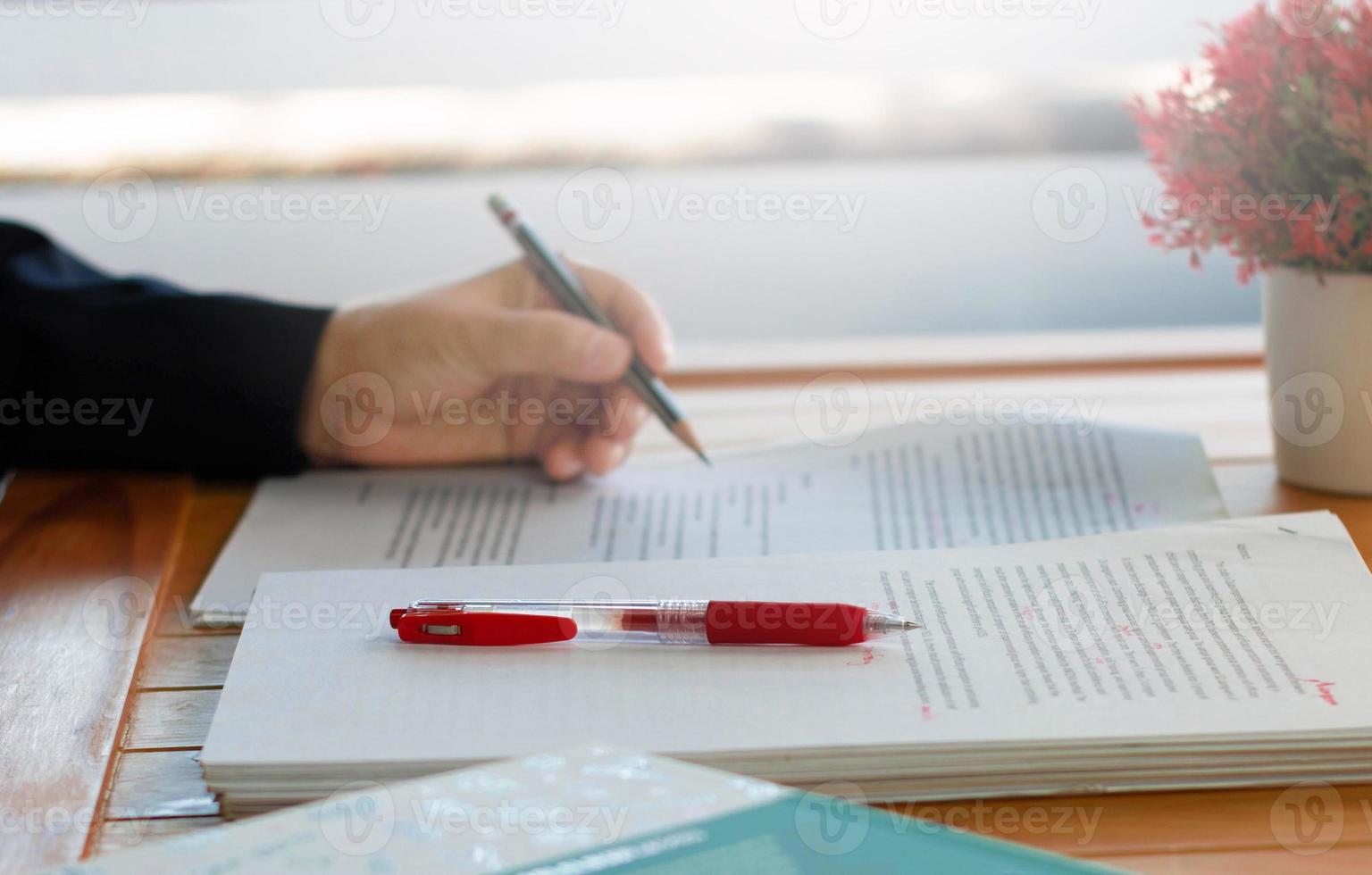 red pen on blurred paperwork and books photo
