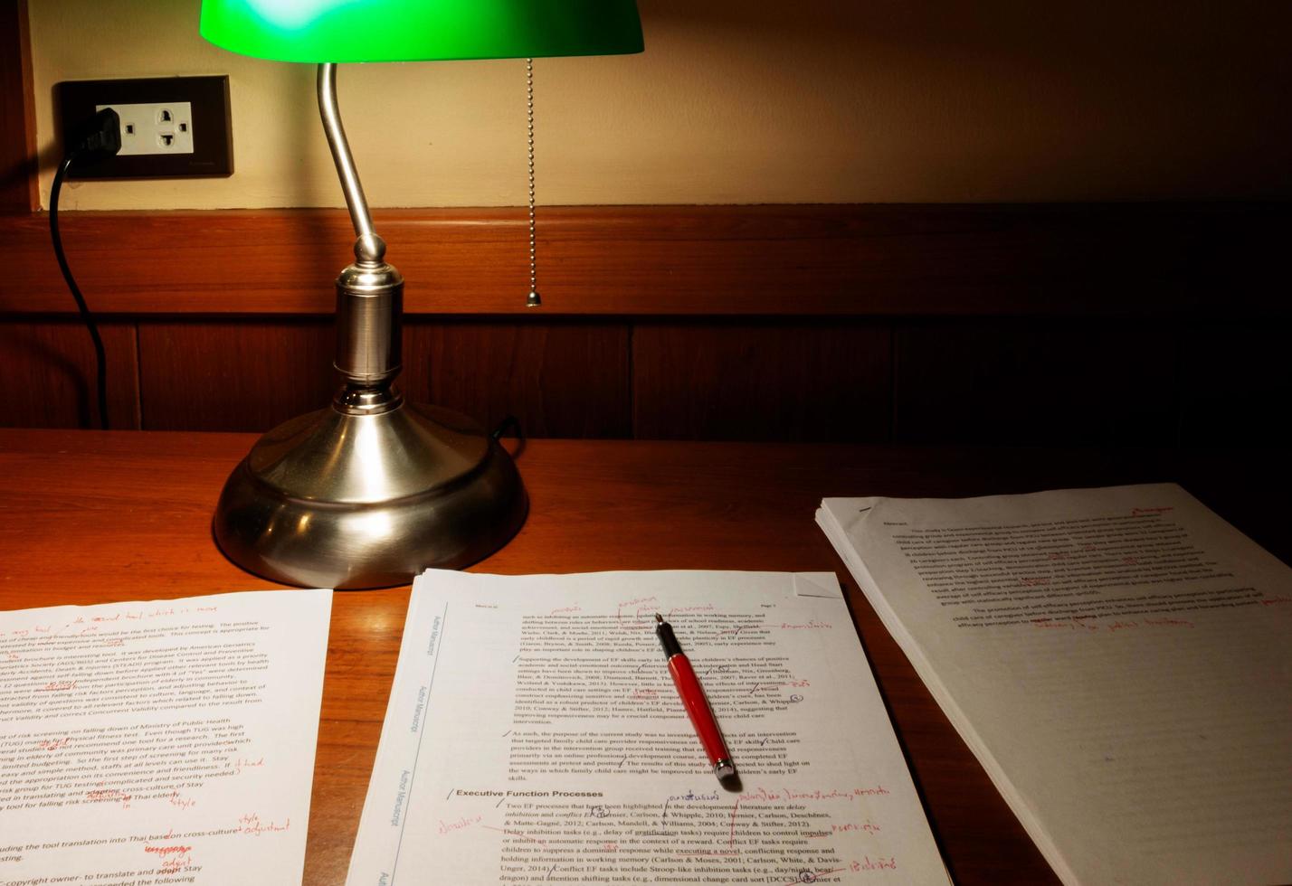 proofreading paper on wooden table under lamp light photo
