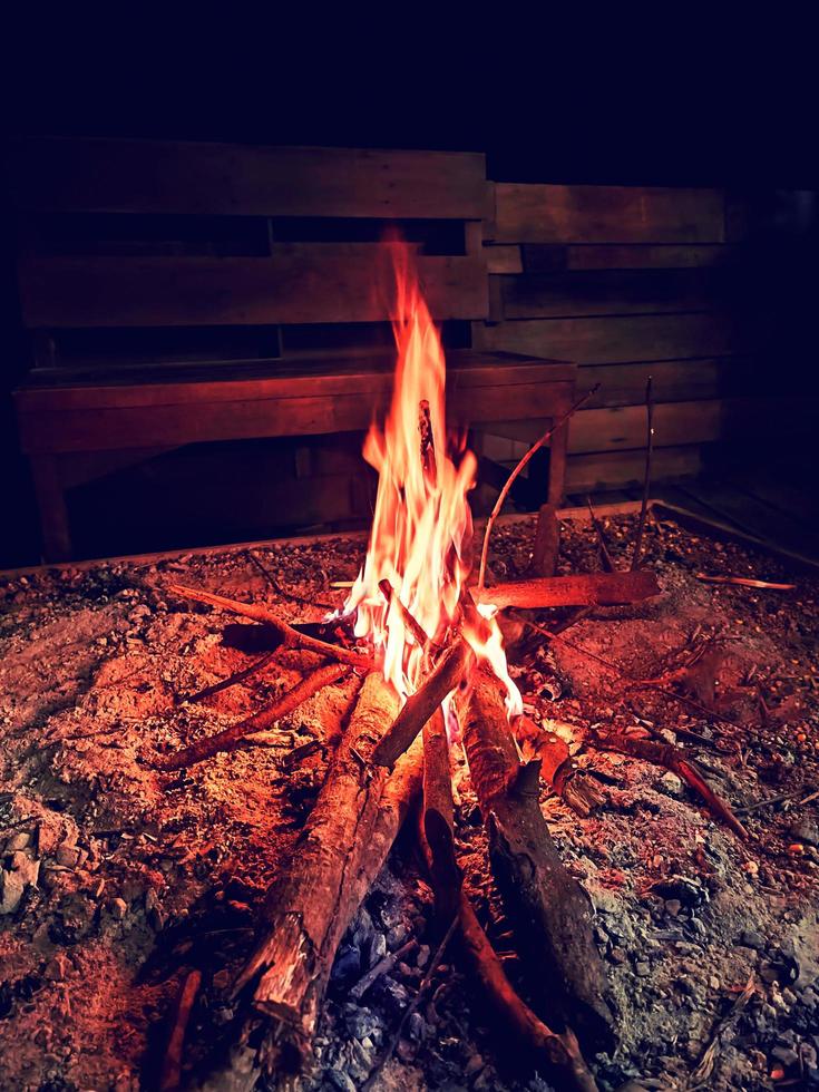 red bonfire in sandbox by wooden bench photo