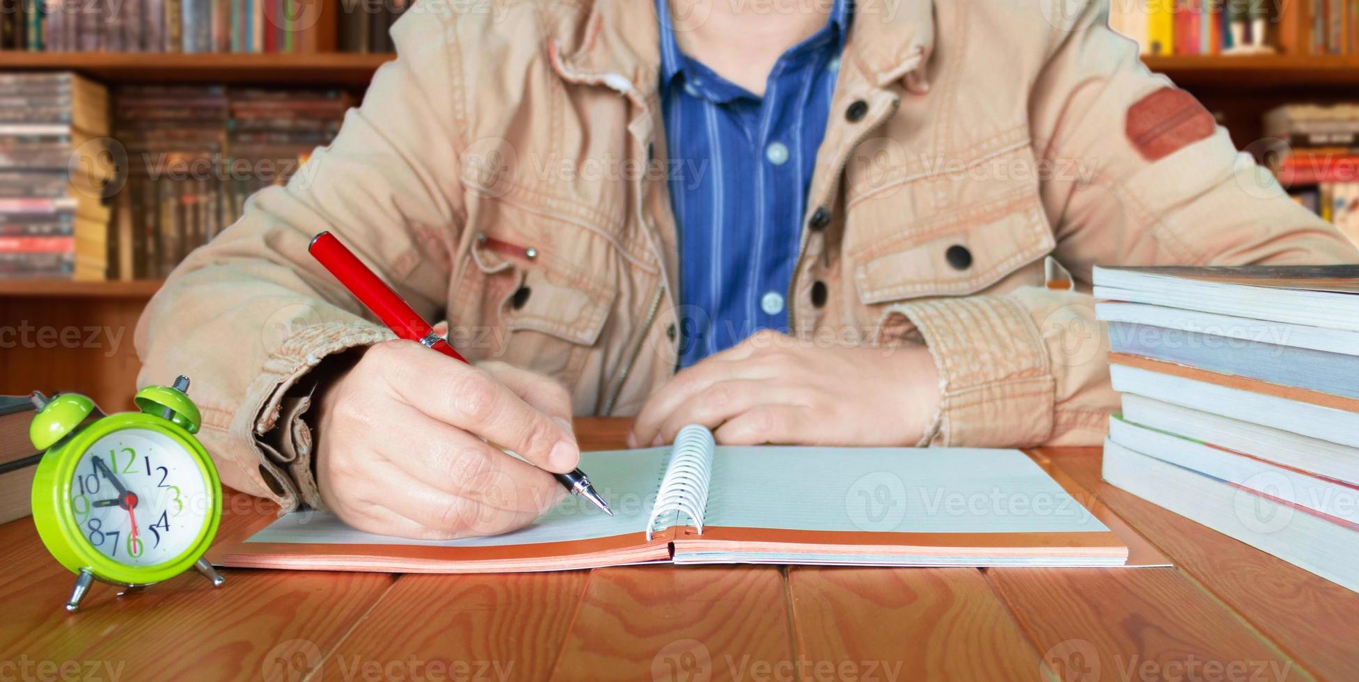 hand writing on notebook  with blurred bookshelf background photo