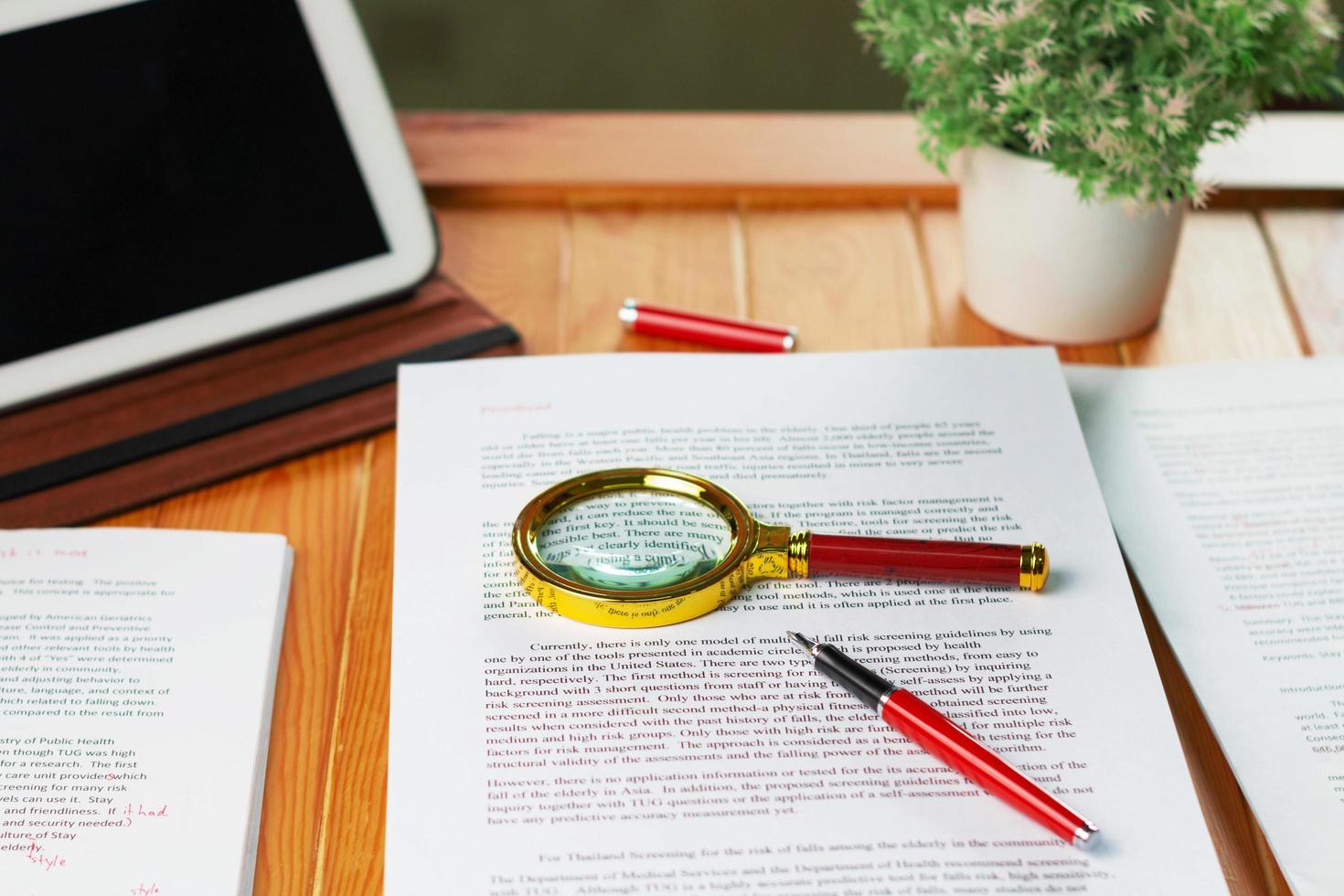 new golden maginifier on proofreading paper on wooden table with office supply photo