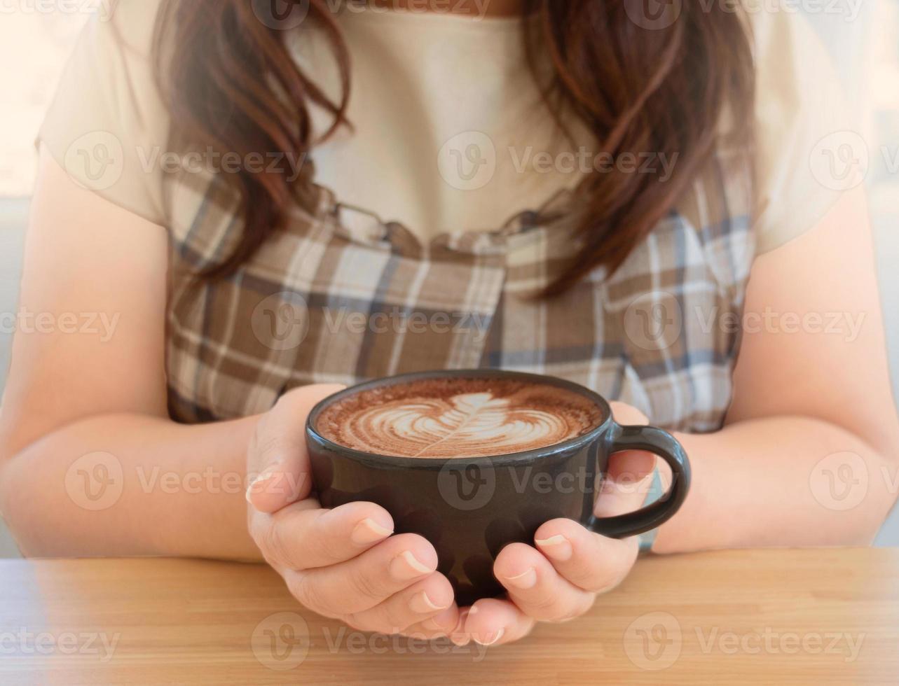 mano sosteniendo una taza de cacao orgánico caliente con arte de espuma de espuma foto