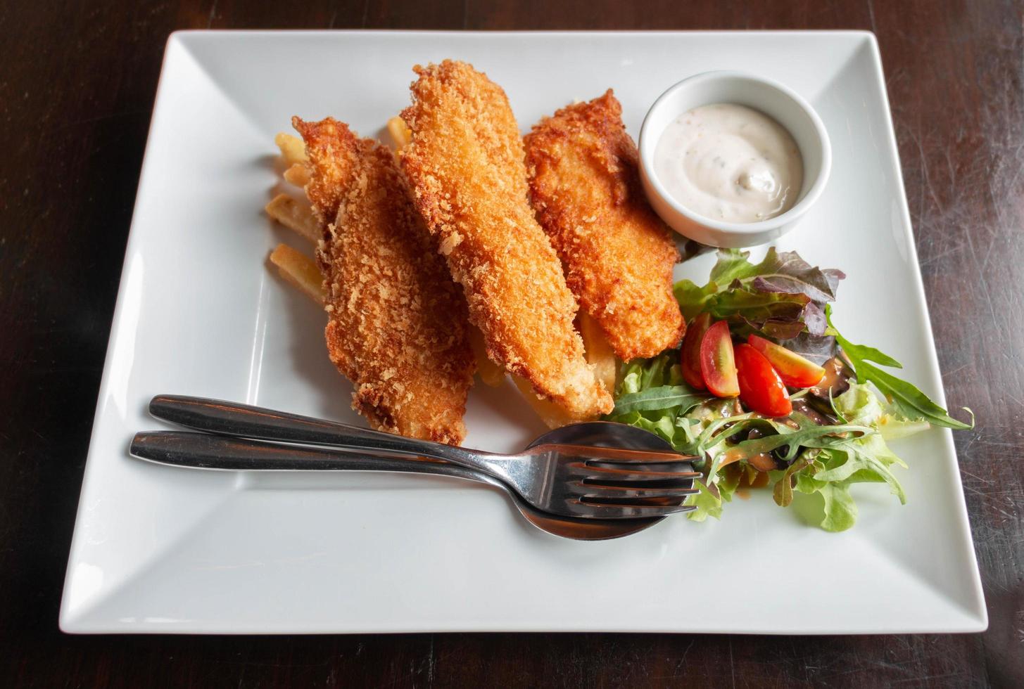 pescado frito y patatas fritas con ensalada y salsa agria foto