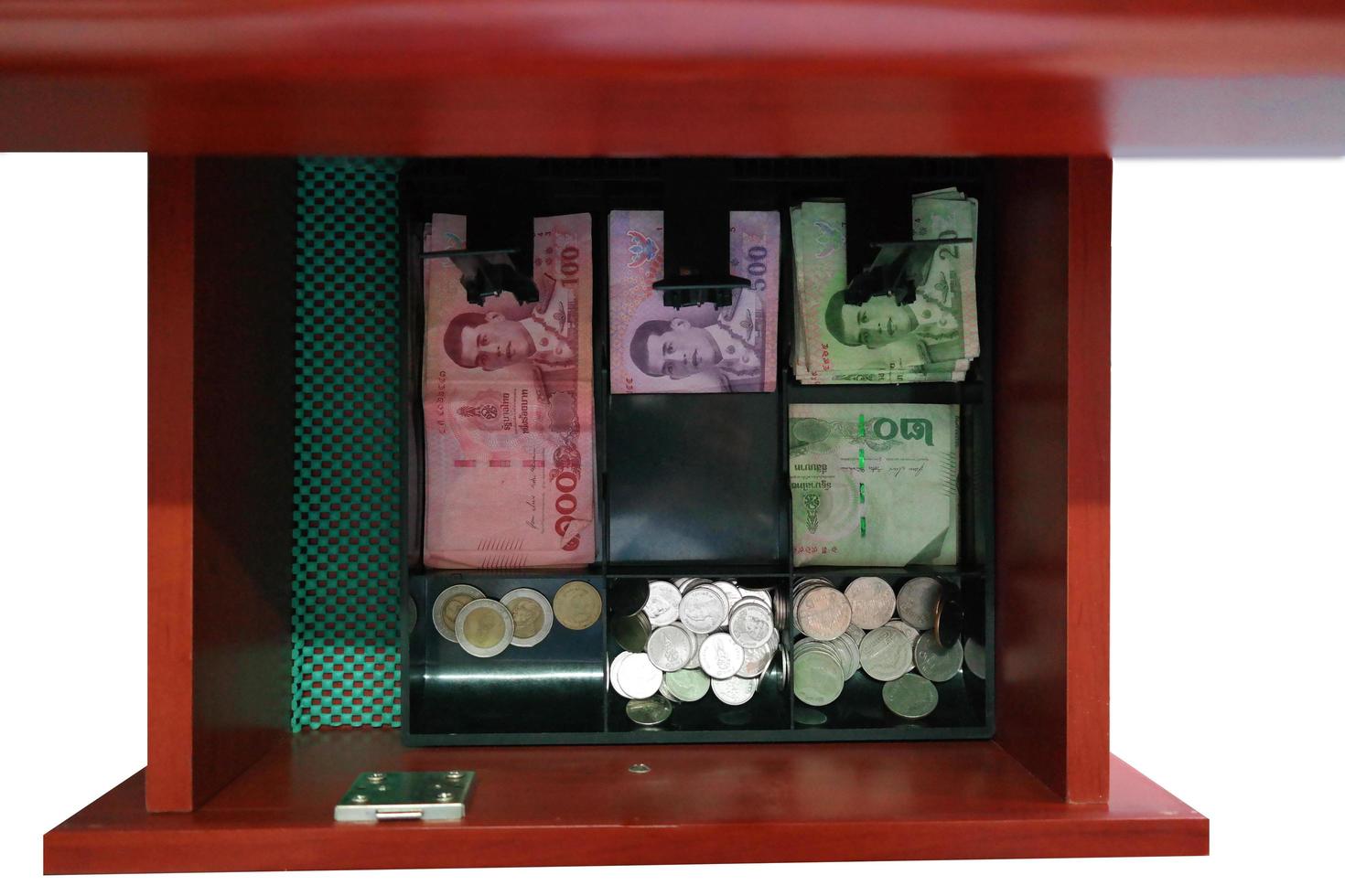 vista superior de los billetes y monedas tailandeses en el cajón del cajero de la tienda minorista foto
