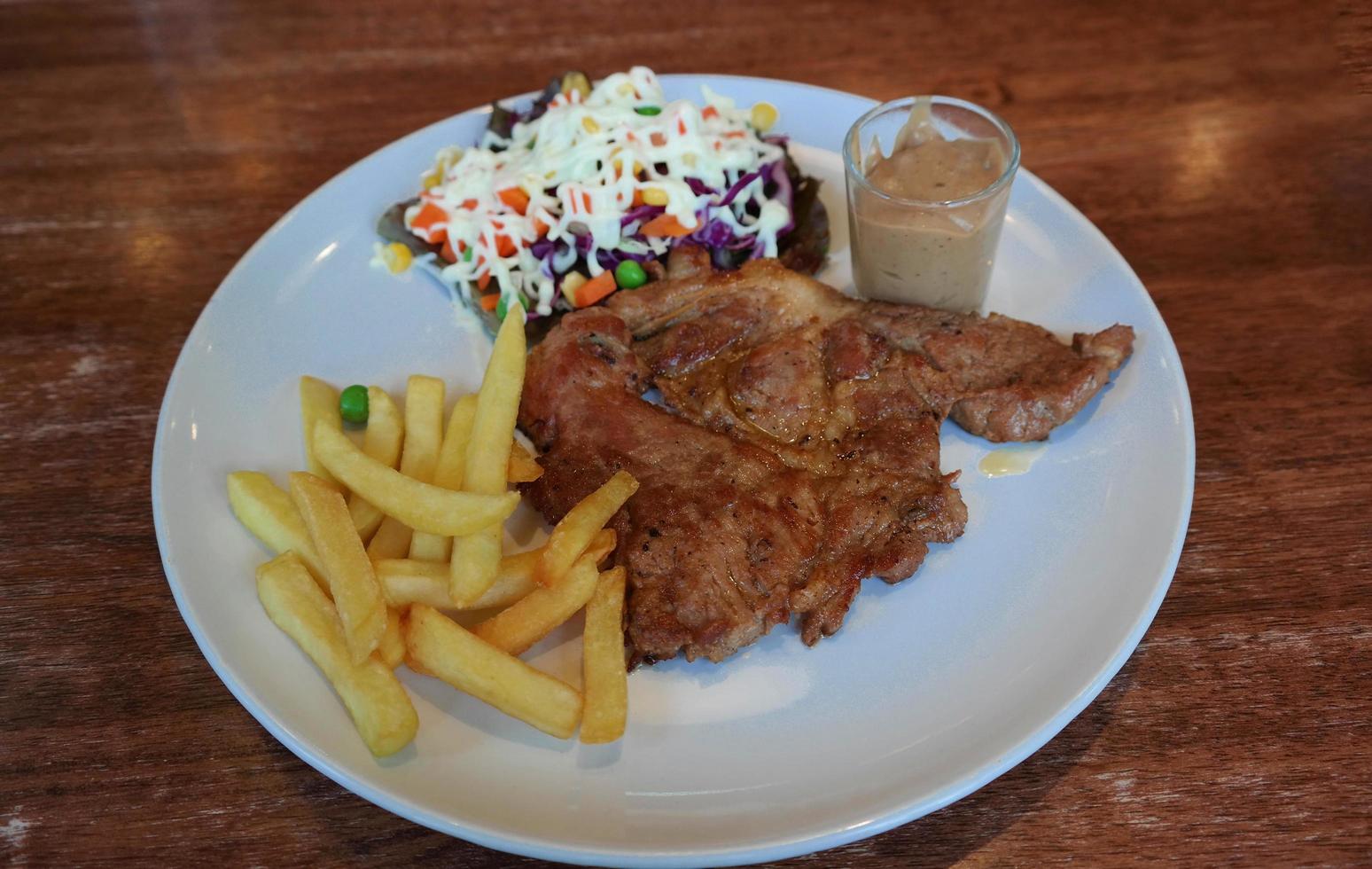 juicy black pepper pork steak with fries and salad photo